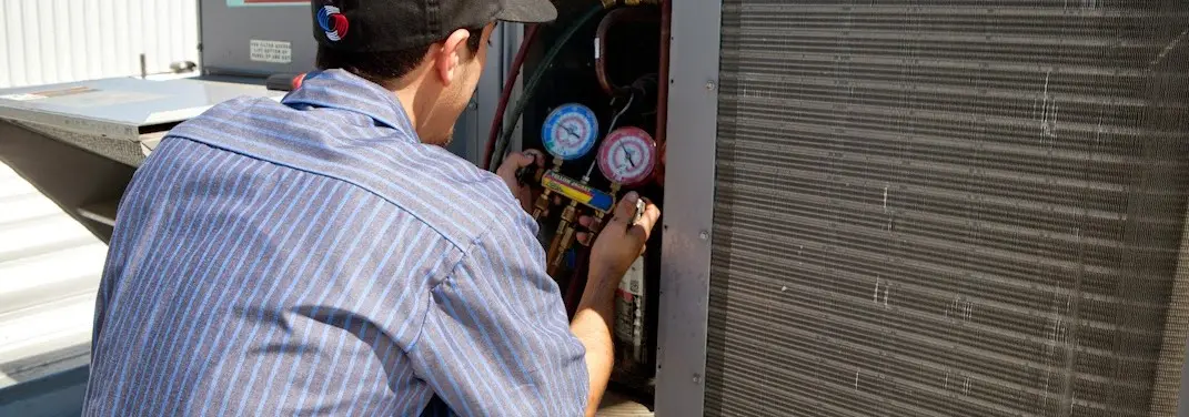 HVAC technician servicing a condenser unit in Torrington